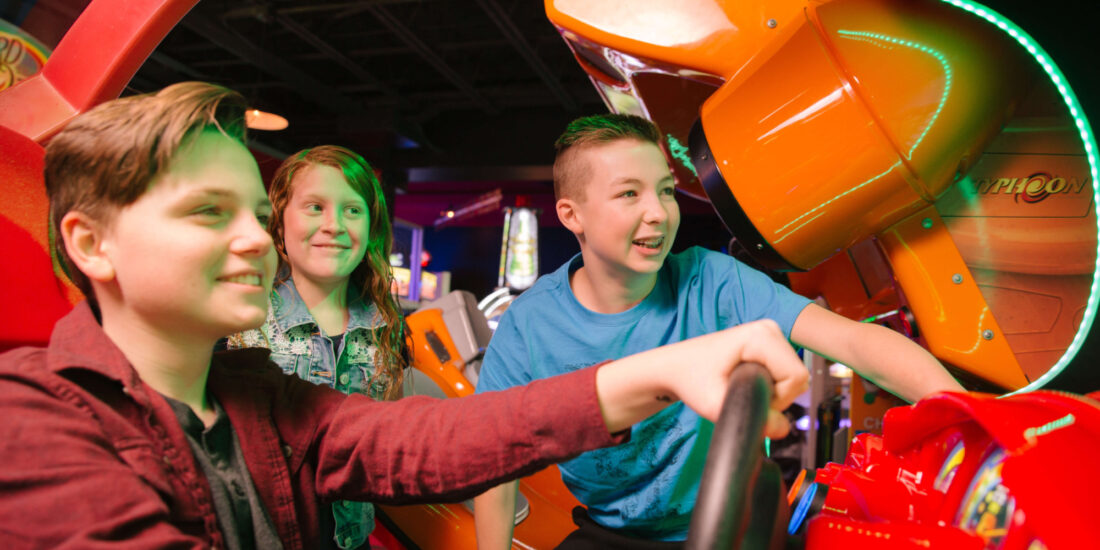 Three kids have fun playing an arcade game at Andy B's kids' birthday parties